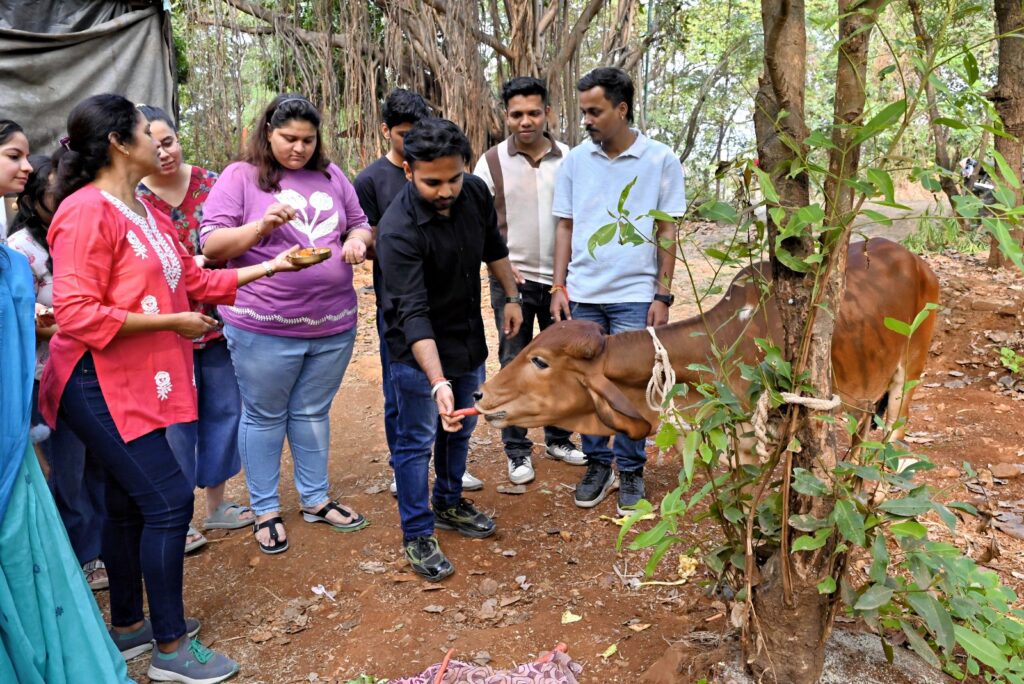 A group of Shivam Autozone employees gathered under a large tree during a CSR initiative in a rural setting. One team member is kneeling to gently feed a young brown calf, while others look on with bowls of offerings. This event demonstrates Shivam Autozone’s commitment to social responsibility and sustainability by supporting animal welfare and engaging directly with Maharashtra and Mumbai communities to create a lasting community impact.