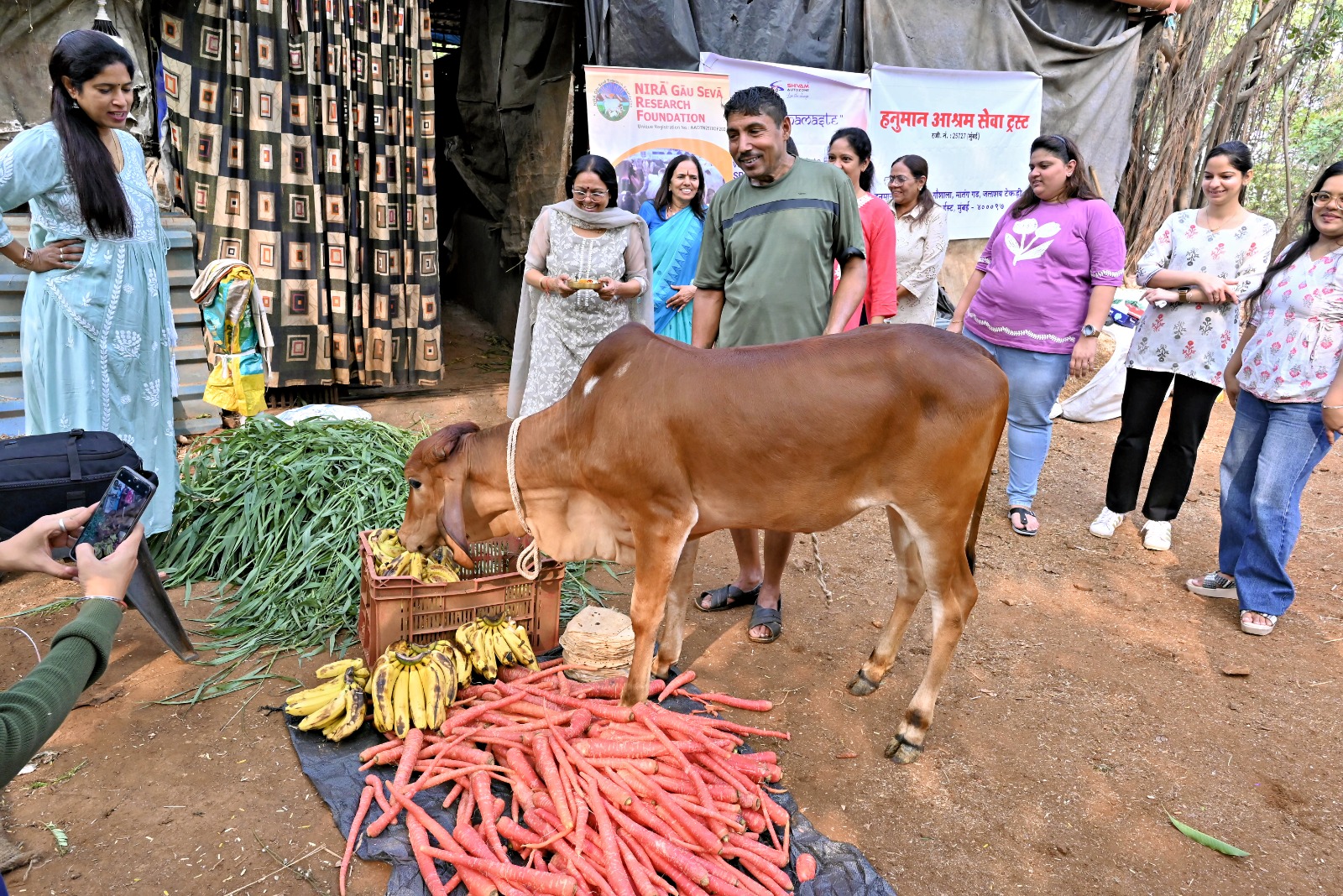 Volunteers from Shivam Autozone participating in CSR initiatives by feeding a calf fresh bananas and carrots. In the background, event banners highlight the collaboration with Maharashtra and Mumbai communities. This initiative showcases Shivam Autozone’s commitment to social responsibility and creating a positive community impact through local animal welfare programs.